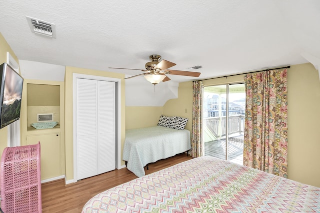 bedroom with access to exterior, ceiling fan, wood-type flooring, and a textured ceiling