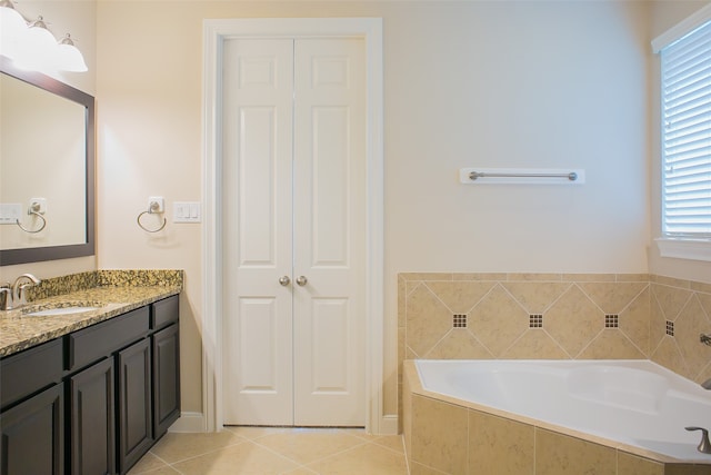 bathroom featuring tile patterned floors, vanity, and tiled bath