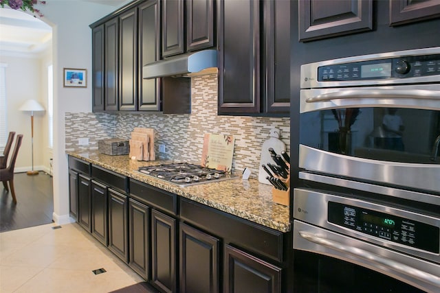 kitchen featuring decorative backsplash, appliances with stainless steel finishes, light stone counters, ornamental molding, and light tile patterned floors