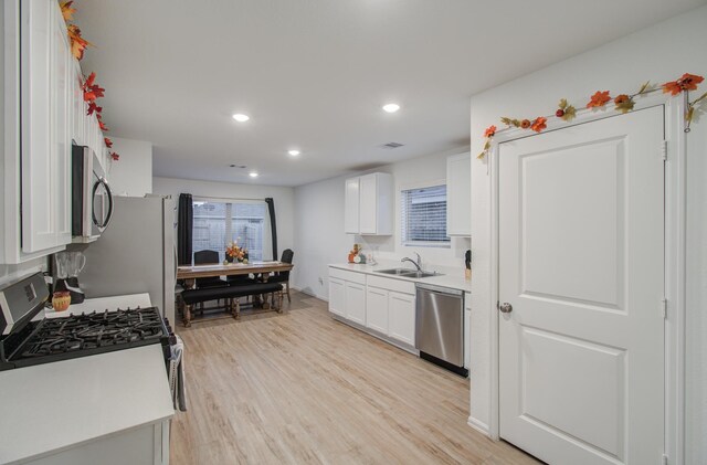 kitchen featuring white cabinets, appliances with stainless steel finishes, light wood-type flooring, and sink