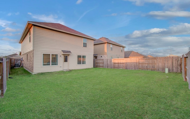 rear view of property featuring a lawn and cooling unit