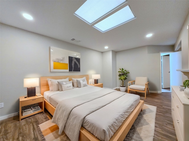 bedroom with hardwood / wood-style floors and a skylight