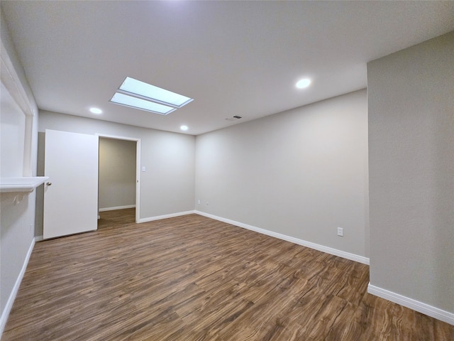 spare room featuring dark hardwood / wood-style flooring and a skylight