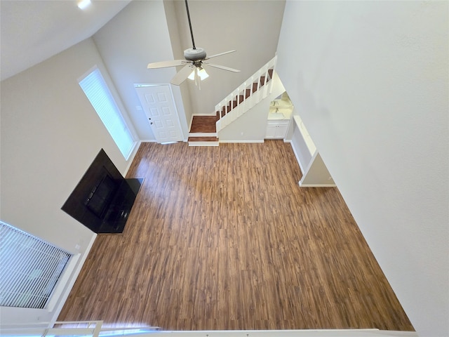 unfurnished living room with wood-type flooring, high vaulted ceiling, and ceiling fan