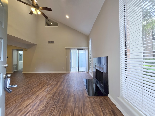 unfurnished living room with ceiling fan, a tile fireplace, dark wood-type flooring, and high vaulted ceiling