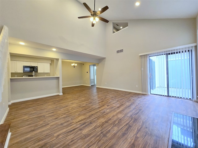 unfurnished living room featuring dark hardwood / wood-style floors, ceiling fan with notable chandelier, and high vaulted ceiling