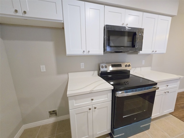 kitchen with white cabinets, stainless steel electric stove, and light tile patterned flooring