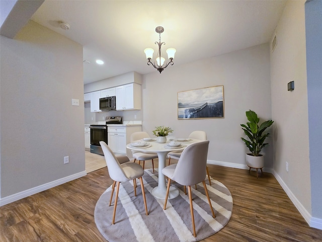 dining area with wood-type flooring and an inviting chandelier