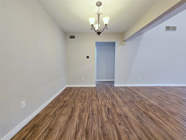 unfurnished room featuring dark wood-type flooring and an inviting chandelier