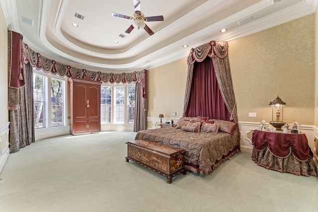 carpeted bedroom with a raised ceiling, ceiling fan, and crown molding