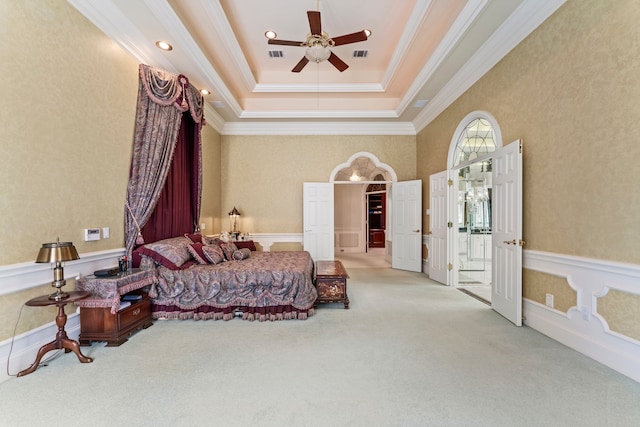 bedroom featuring a tray ceiling, ceiling fan, light carpet, and ornamental molding