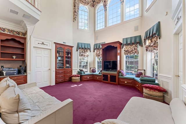 carpeted living room featuring a towering ceiling and crown molding