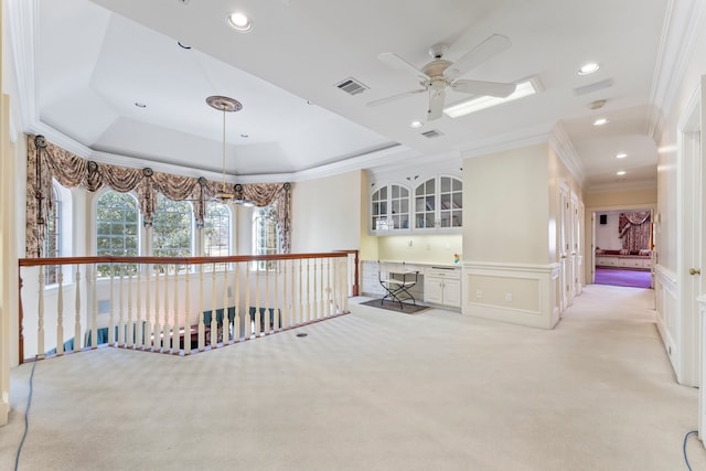 interior space with light colored carpet, ornamental molding, and a tray ceiling