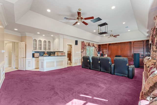 home theater room with a tray ceiling, light carpet, crown molding, and ceiling fan