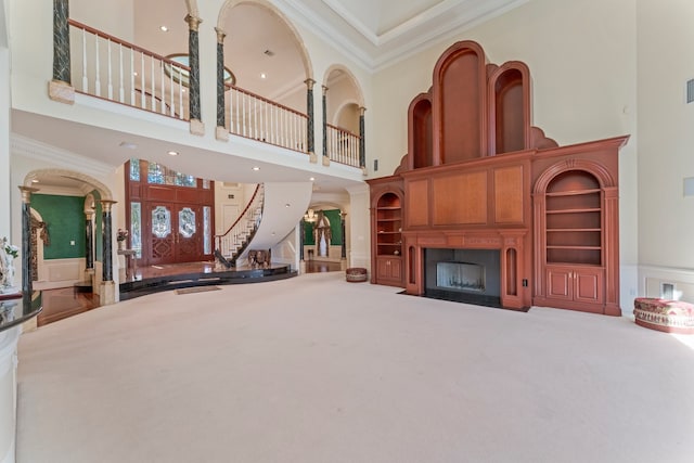 living room featuring built in shelves, carpet, a high ceiling, and ornamental molding