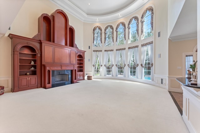 carpeted living room featuring a towering ceiling and ornamental molding