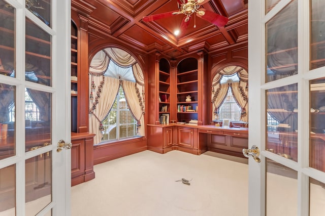 carpeted office featuring french doors, coffered ceiling, crown molding, built in desk, and beam ceiling