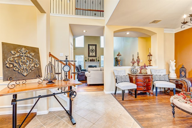 foyer entrance with a towering ceiling, light hardwood / wood-style floors, and crown molding