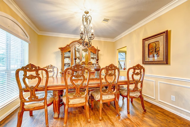 dining area with a chandelier, hardwood / wood-style flooring, and ornamental molding