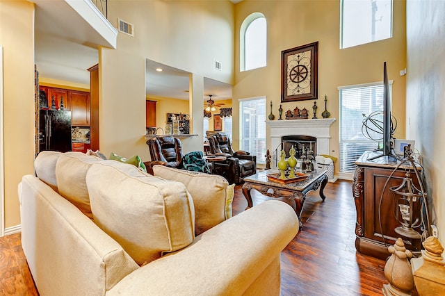 living room featuring a high ceiling, ceiling fan, and dark wood-type flooring