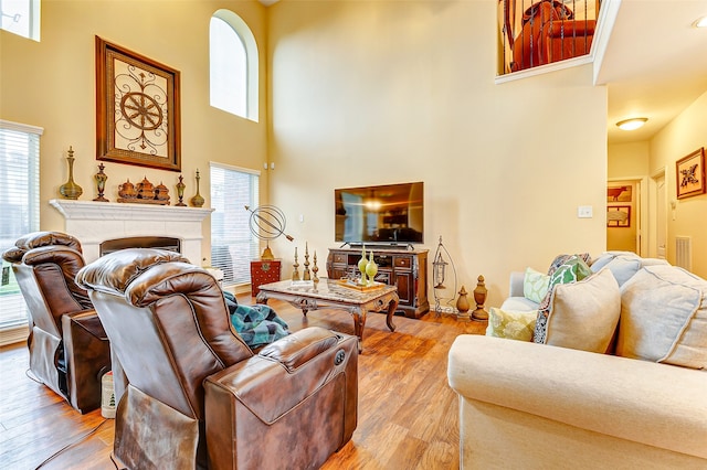 living room with a towering ceiling, light hardwood / wood-style flooring, and a healthy amount of sunlight