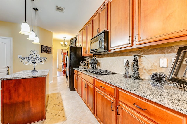 kitchen featuring tasteful backsplash, light stone counters, stainless steel appliances, light tile patterned floors, and a kitchen island