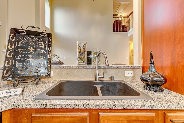 kitchen featuring light stone counters, sink, and tasteful backsplash