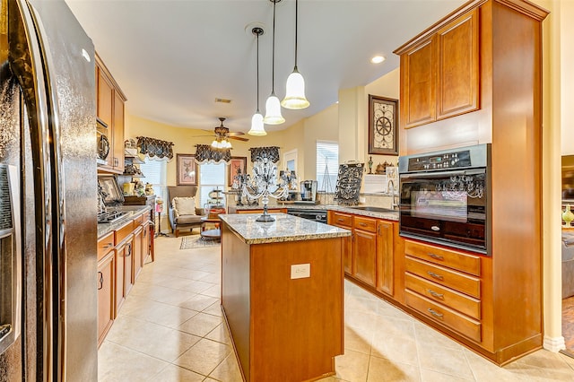 kitchen with black appliances, plenty of natural light, a center island, and decorative light fixtures