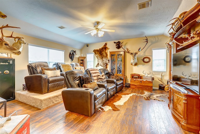 living room featuring ceiling fan, wood-type flooring, lofted ceiling, and a textured ceiling