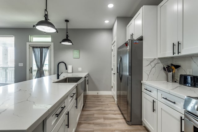 kitchen featuring light stone countertops, white cabinets, stainless steel appliances, and decorative light fixtures