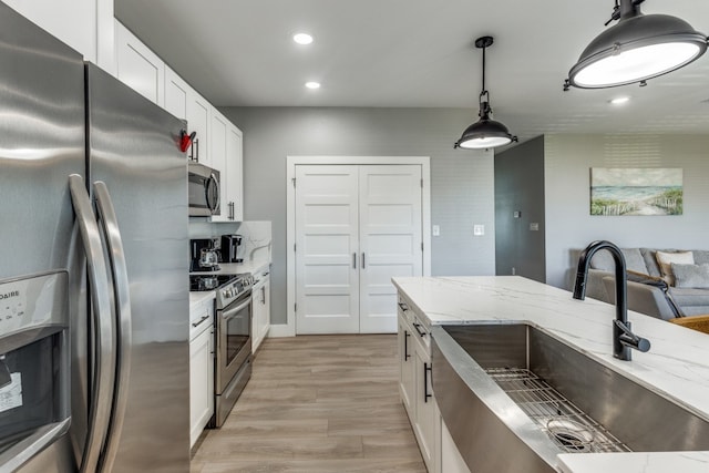 kitchen featuring white cabinets, pendant lighting, sink, and appliances with stainless steel finishes