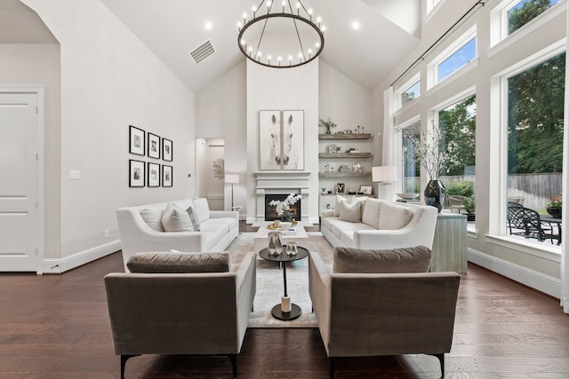 living room with a chandelier, high vaulted ceiling, a healthy amount of sunlight, and dark hardwood / wood-style floors