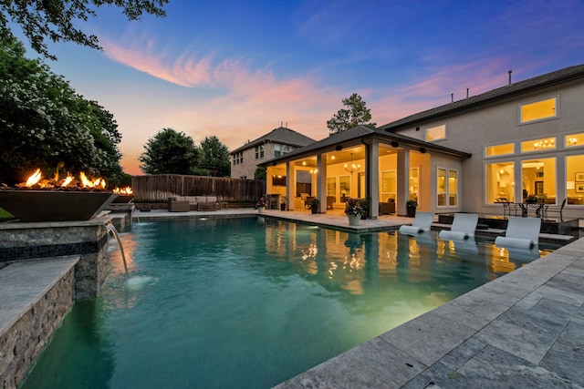 pool at dusk with pool water feature and a patio