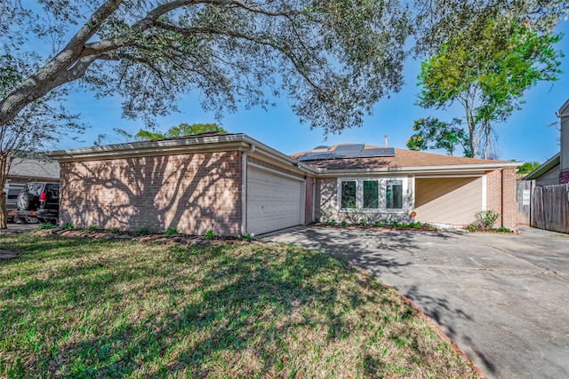 ranch-style home with a front yard, solar panels, and a garage