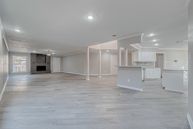 unfurnished living room featuring ceiling fan, light hardwood / wood-style floors, ornamental molding, and a fireplace