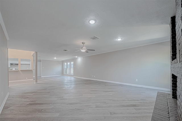 unfurnished living room with ceiling fan, ornamental molding, light wood-type flooring, and a brick fireplace