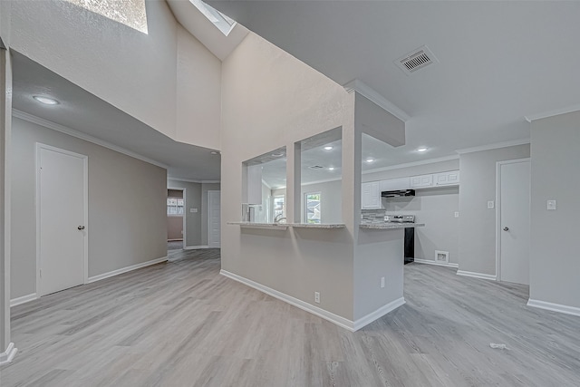 kitchen with kitchen peninsula, a skylight, electric stove, light hardwood / wood-style flooring, and white cabinets