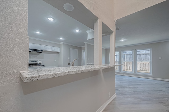 kitchen with white cabinetry, kitchen peninsula, crown molding, stainless steel electric range, and light wood-type flooring