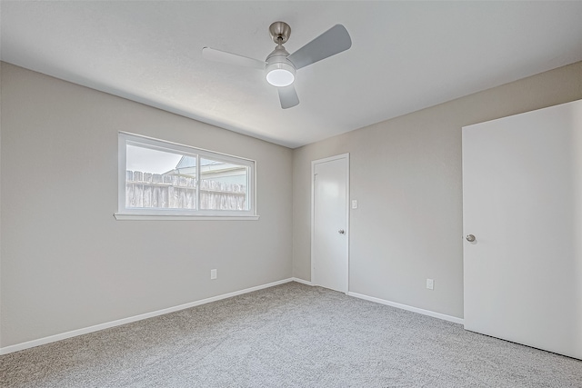 empty room featuring ceiling fan and light colored carpet