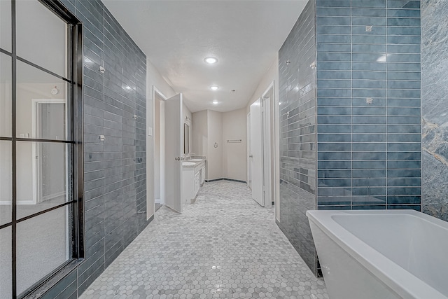 bathroom featuring tile patterned flooring, vanity, tile walls, and a bathing tub