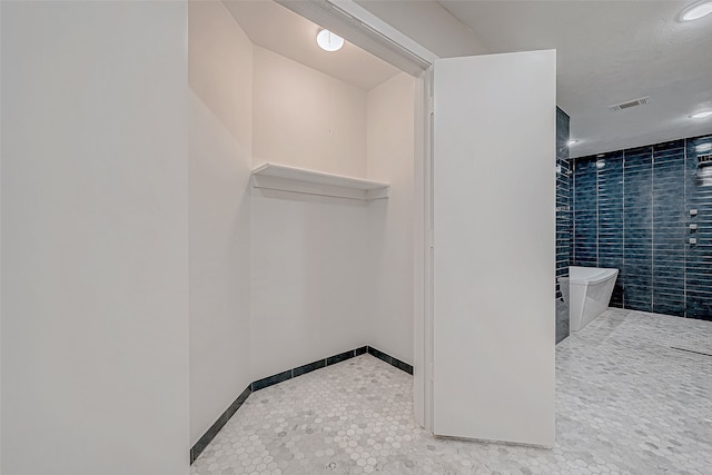 bathroom with tile patterned floors and a tub to relax in