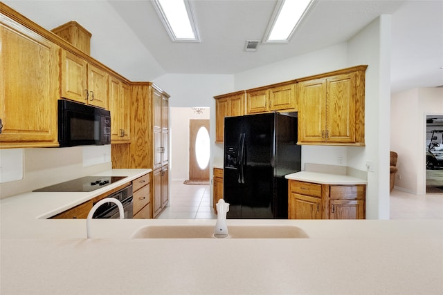 kitchen with kitchen peninsula, light tile patterned flooring, and black appliances