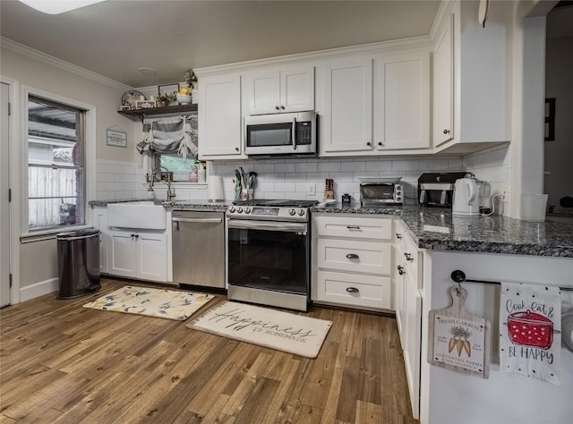 kitchen with white cabinets, crown molding, sink, and stainless steel appliances