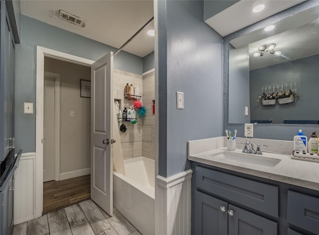 bathroom featuring hardwood / wood-style floors, vanity, and shower / tub combination