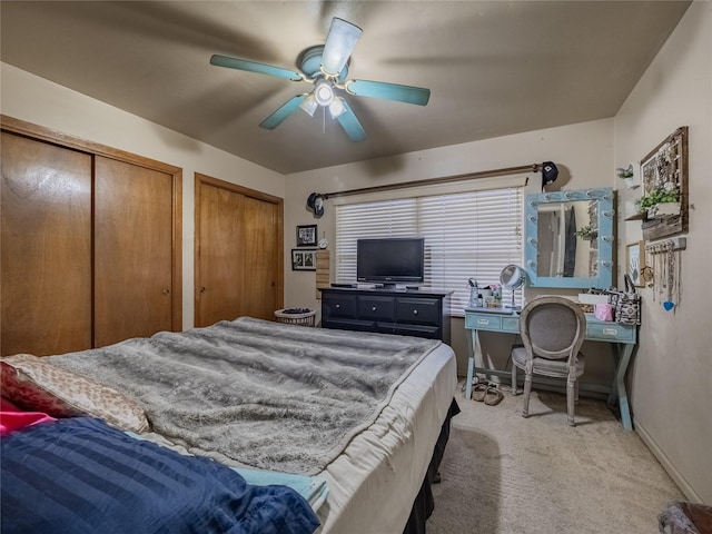 bedroom featuring multiple closets, ceiling fan, and light carpet