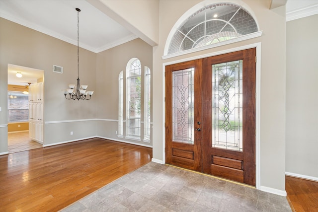 entryway with hardwood / wood-style floors, ornamental molding, french doors, and a notable chandelier