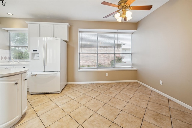 kitchen featuring white cabinets, light tile patterned floors, white fridge with ice dispenser, and ceiling fan