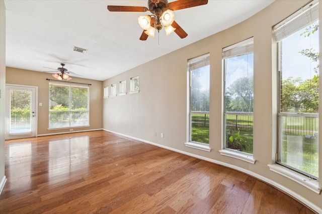 empty room with hardwood / wood-style floors, ceiling fan, and a wealth of natural light