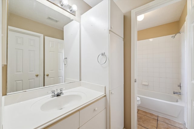 full bathroom featuring tile patterned floors, vanity, tiled shower / bath combo, and toilet