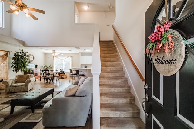 staircase featuring ceiling fan, hardwood / wood-style floors, and a high ceiling